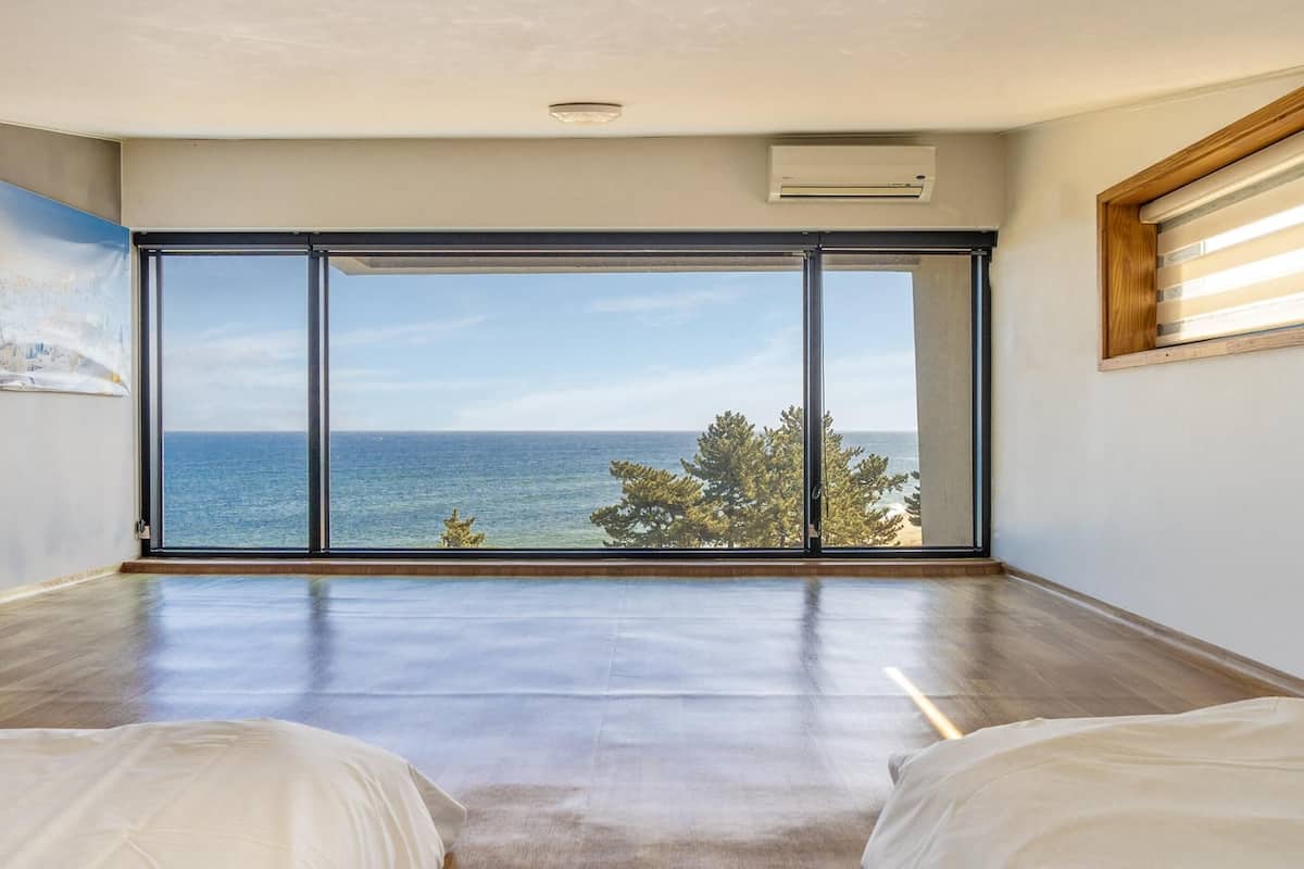 Een kamer met een grote schuifglazen deur die uitkomt op een balkon met uitzicht op zee.