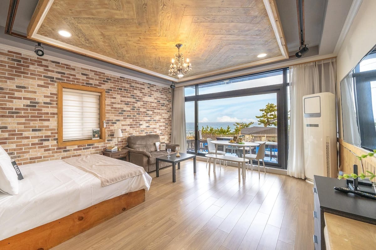 Een slaapkamer met een bakstenen muur, een groot bed, een bureau en uitzicht op zee.