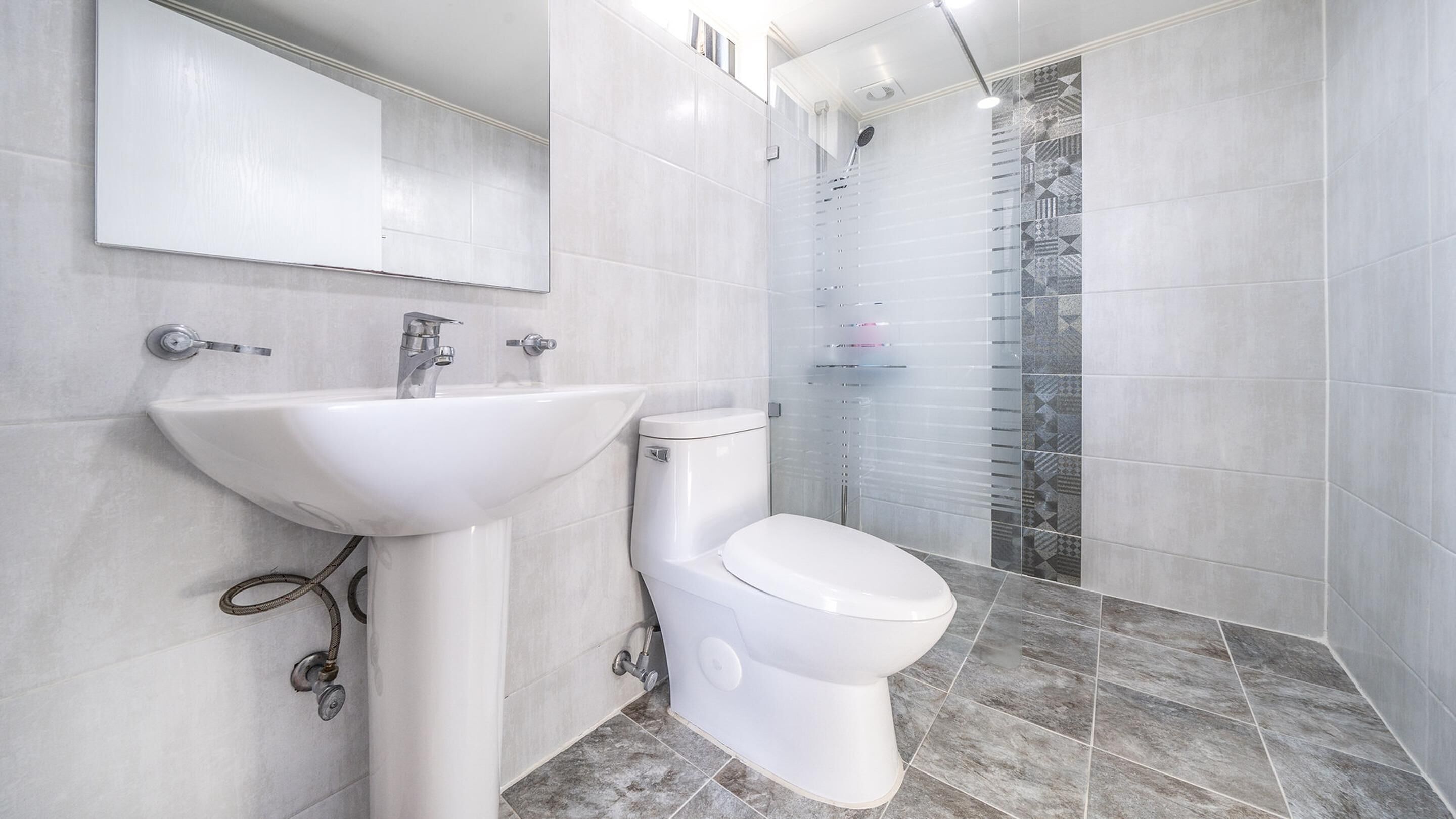 A modern bathroom with a white sink, toilet, and shower.