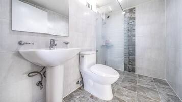 A modern bathroom with a white sink, toilet, and shower.