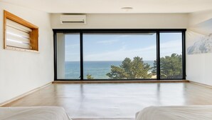 A spacious room with a large sliding glass door leading to a balcony with a sea view. - Gangneung Jd38 spa Pension (Gangneung)