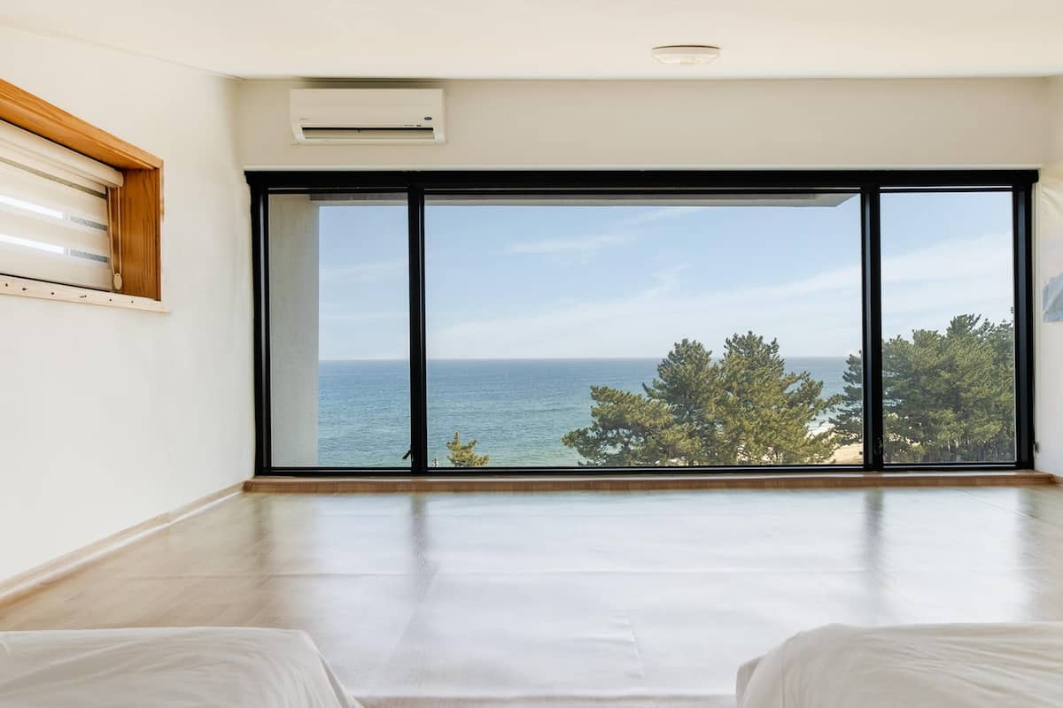 Een ruime kamer met een grote schuifpui die uitkomt op een balkon met uitzicht op zee.