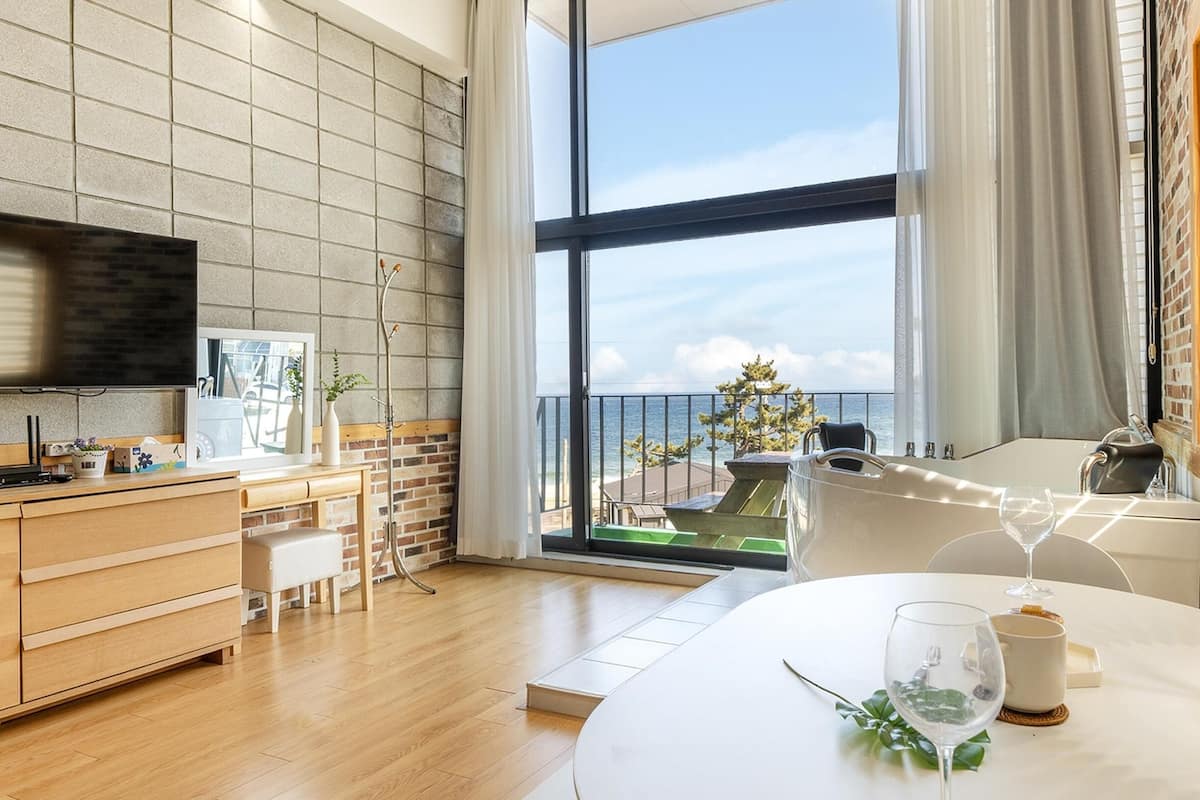 Een moderne keuken met een groot raam, een eethoek met een gedekte tafel voor twee personen, en uitzicht op de oceaan.