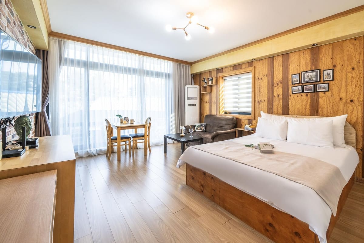 Een hotelkamer met een houten lambrisering, een groot bed, een eettafel met stoelen en een televisie.