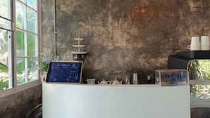 Una reception con uno schermo digitale, un oggetto decorativo e una finestra vista verde.