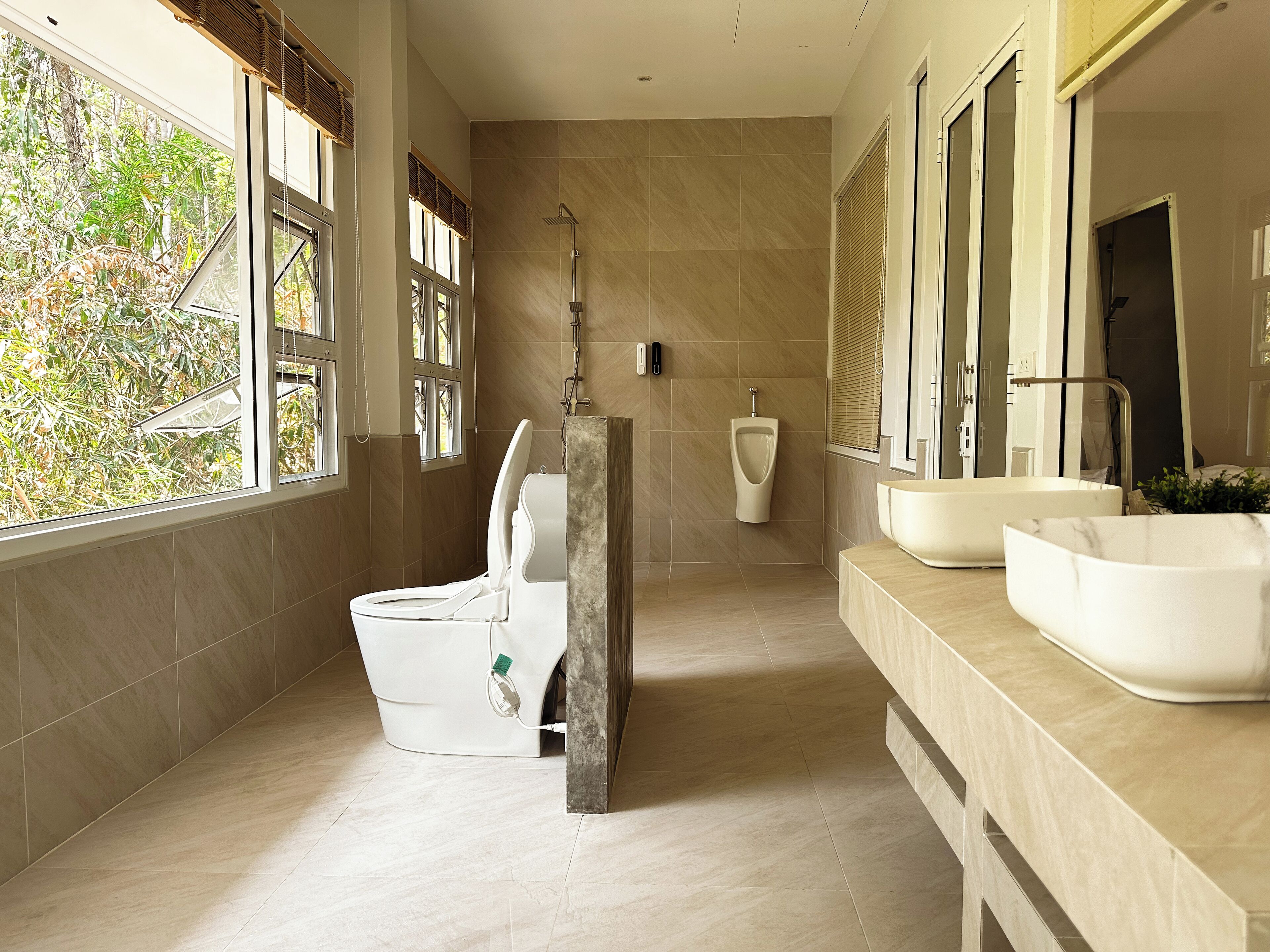 A modern bathroom with a toilet, urinal, and large sinks.