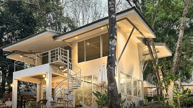 Una moderna casa a due piani con un balcone, ampie finestre e una scala.