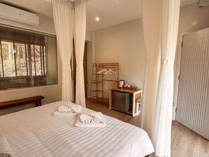 A hotel room with a bed, a small refrigerator, a wooden drying rack, and a window with blinds. - Arb Pa Home & Cafe Chiang Mai (Mae On)