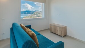 Ein modernes Wohnzimmer mit großem Fenster, einem blauen Sofa und einem Holzschrank.