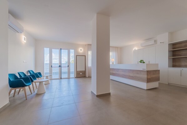 A spacious living area with a modern kitchen, a dining area with blue chairs, and large glass doors leading to a balcony.