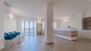 A spacious living area with a modern kitchen, a dining area with blue chairs, and large glass doors leading to a balcony.