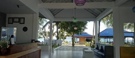 A spacious lobby with a reception desk, seating areas, and a view of the beach.