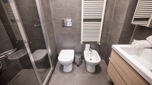 Een moderne badkamer met toilet, bidet en bad.
