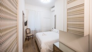 Een hotelkamer met een bed, een stoel, een nachtkastje en een spiegel.
