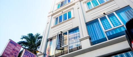 Un hôtel à plusieurs étages, doté d’une architecture classique, de grandes fenêtres et d’une enseigne bien visible.