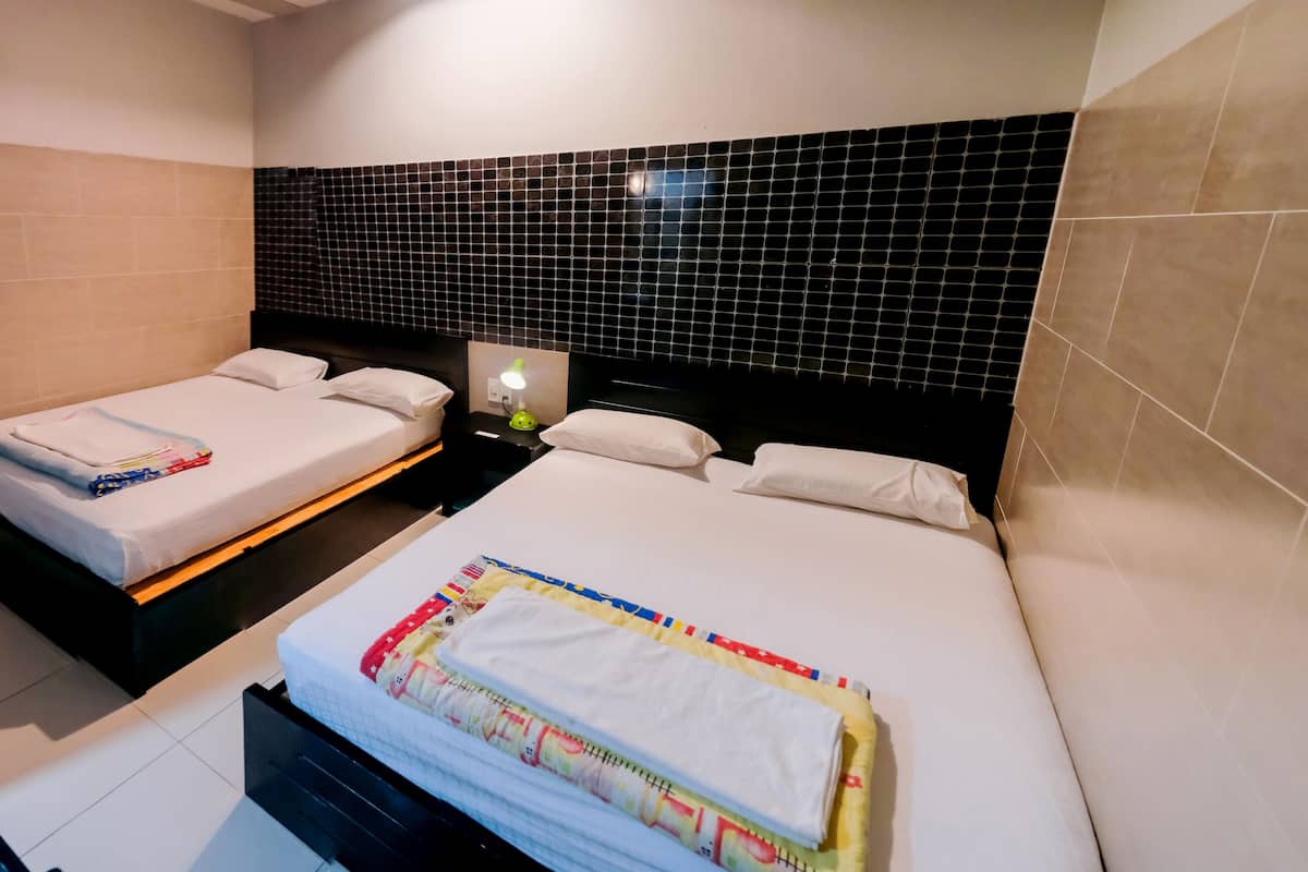 A hotel room with two beds, a nightstand, and a desk with a chair.