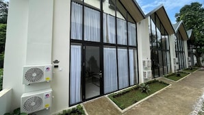 A modern building with large windows, air conditioning units, and a paved walkway with small planters. - Azana Essence Sanggabuana Bogor (Bogor)