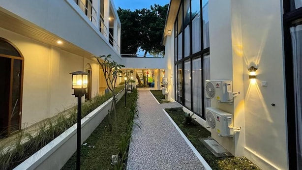 A modern building with a pathway leading to a central area, surrounded by white walls and large windows. - Azana Essence Sanggabuana Bogor (Bogor)