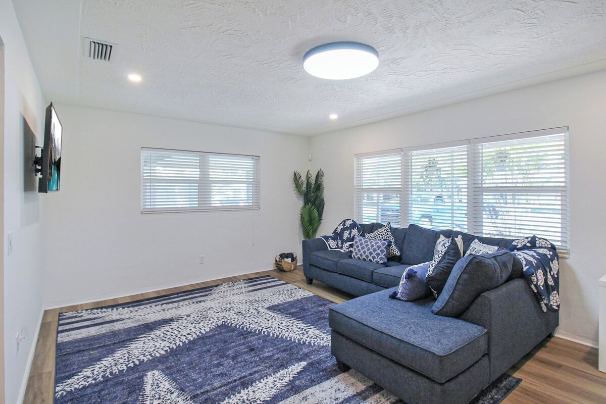 Ein Wohnzimmer mit grauem Sofa, einem gemusterten Teppich und einer Deckenleuchte.