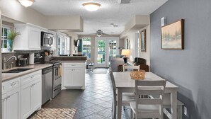 A modern kitchen with white cabinets, a microwave, and a dining area with a table and chairs. - The Marlin House: Waterfront Escape with Dock, Outdoor Kitchen & Stunning Views! (Willis)