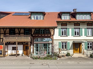 A traditional European building with a sloped roof, wooden balconies, and a ground-floor shop with outdoor seating.