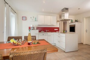 Une cuisine moderne avec des meubles blancs, un pare-feu rouge et un îlot central.