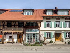 Un bâtiment européen traditionnel, doté d’un toit en pente, de balcons en bois et d’un commerce au rez-de-chaussée avec une terrasse.