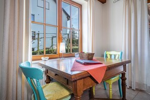 Un coin repas avec une table en bois, des chaises, un panier et un ordinateur portable.