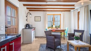 Una cocina con un electrodoméstico rojo, una zona de comedor con mesa y sillas, y un espacio de estar con sofá y una mesa.