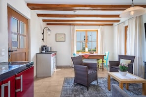 Une cuisine avec un appareil électroménager rouge, un coin repas avec une table et des chaises, et un espace détente avec un canapé et une table.
