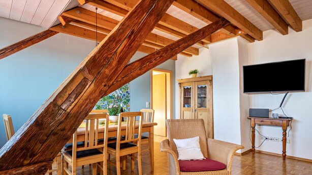 A dining area with wooden furniture, a television, and a staircase. - Apartment "Kornboden" with Shared Garden, Balcony, and Wi-Fi (Immenstaad am Bodensee)