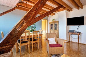 A dining area with wooden furniture, a television, and a staircase.