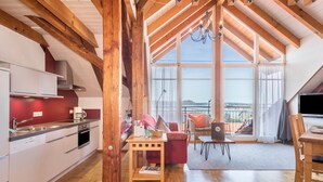 Una cucina moderna con mobili bianchi, soffitto in legno e zona pranzo con divano rosso e un portatile.