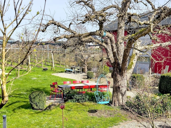 A garden with a swing set, red chairs, and a table.