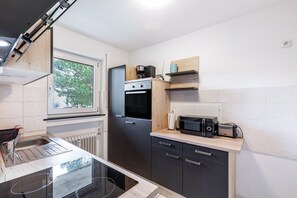 A compact kitchen with a built-in oven, a microwave, and a window with a view of trees.