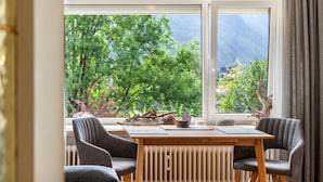 A room with a table and chairs, a window with a view of trees and mountains, and a radiator.