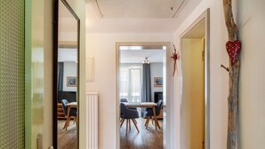 Ein Innenraum von Hotelzimmern mit Holzboden, einem Essbereich mit Tisch und Stühlen und einem Spiegel, der den Raum reflektiert.