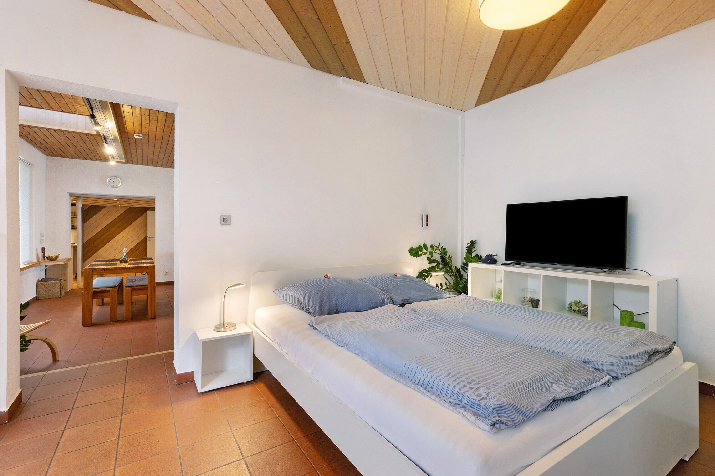 A bedroom with a bed, a TV, and a small desk area.