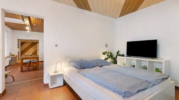 A bedroom with a bed, a TV, and a small desk area.