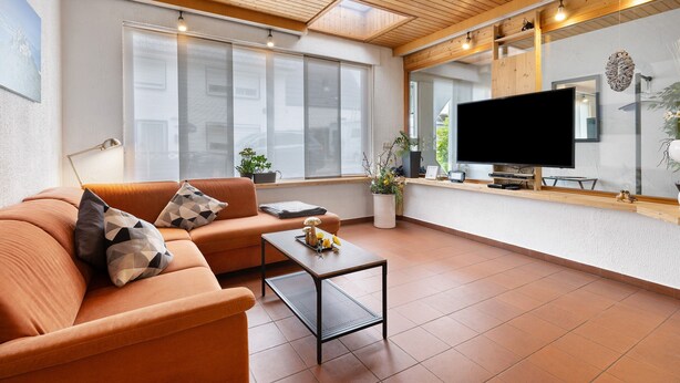 Een moderne woonkamer met een bank, salontafel en een flatscreen televisie.