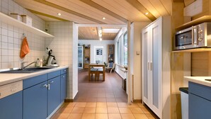 Een keuken met blauwe kastjes, een houten plafond en een eethoek met een tafel en stoelen.