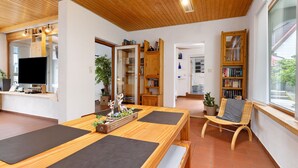 Een houten interieur met een eettafel, stoelen, een boekenkast en een televisie.