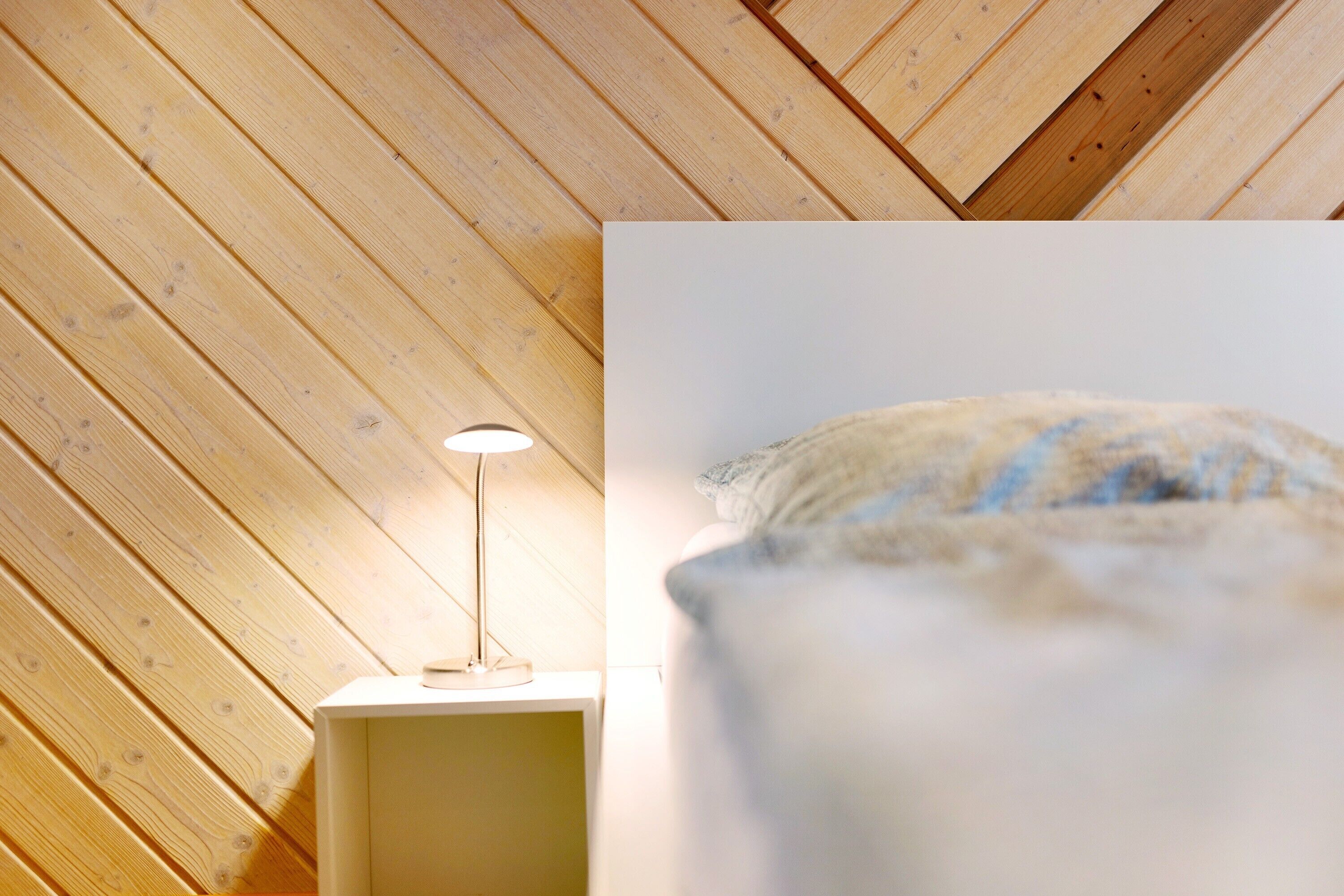 A room with a sloped ceiling, a bedside lamp, and a pillow.