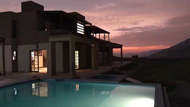 Une maison moderne avec une piscine, au crépuscule.