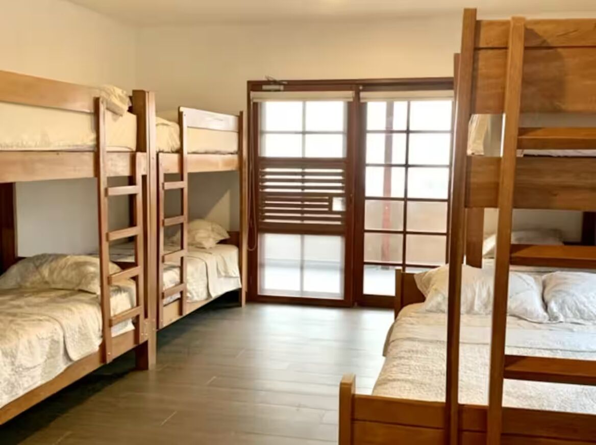 A room with bunk beds, a sliding glass door, and a wooden floor.