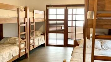 A room with bunk beds, a sliding glass door, and a wooden floor.