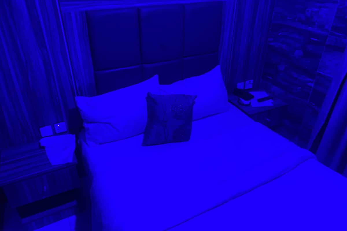 A room with a bed, a nightstand, and a window.