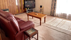 A living room with a leather sofa, a wooden coffee table, a television, and a painting on the wall.