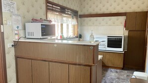 A compact kitchen with wooden cabinets, a microwave, a stove, and a sink.