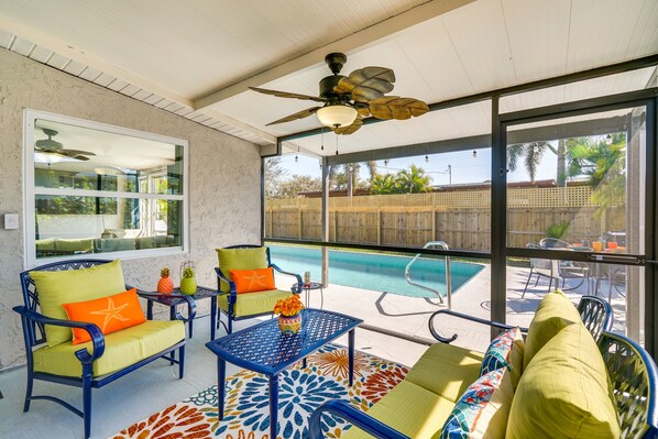 A covered patio with outdoor furniture, a ceiling fan, and a view of a swimming pool. - Port Charlotte Vacation Rental w/ Heated Pool! (Port Charlotte)